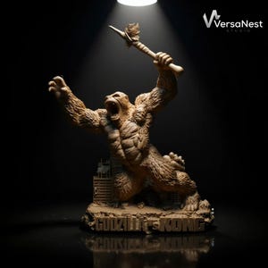 Puede incluir: Escultura detallada de King Kong, sosteniendo una lanza, con la boca abierta y los brazos levantados. La escultura es marrón y beige, con el texto "GODZILLA VS KONG" en la base. El logotipo de VersaNest Studio está en la esquina superior derecha.