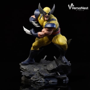 May include: A yellow and blue Wolverine statue in a dynamic pose, with claws extended. The figure has a fierce expression and is set on a rocky base. The VersaNest Studio logo is in the upper right corner.