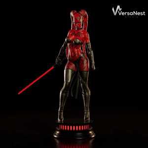Puede incluir: Figura roja y negra de un personaje femenino con cuernos, sosteniendo un sable de luz rojo. La figura está sobre una base negra con luces rojas. El personaje tiene piel roja con marcas negras y viste ropa negra.