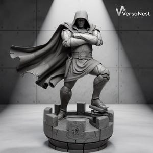 May include: A monochromatic gray resin figurine of a hooded character wearing a tunic, belt, and cape, standing with arms crossed on a circular stone-textured base with a letter D emblem. The figure wears armored gauntlets and leg plates.