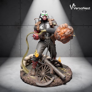 May include: A detailed figurine of a character wearing a white and black helmet, a dark textured suit with a white emblem, and red spiked arm and leg guards. The character holds a large cannon firing an orange explosion, with a gold bullet belt.