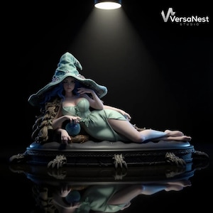 Puede incluir: Figura detallada de una mujer con un vestido verde menta y un sombrero grande a juego. La figura está reclinada sobre una base decorativa con detalles de garras. El logotipo del estudio "VersaNest" es visible en la esquina superior derecha.