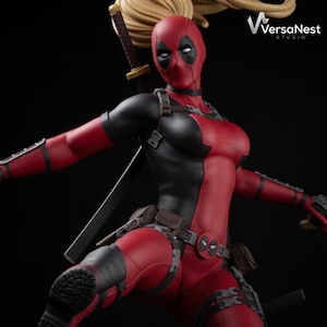 Könnte beinhalten: Detaillierte Statue einer Figur in einem rot-schwarzen Anzug, mit Maske und blonden Haaren. Die Figur ist dynamisch posiert, mit einem Schwert auf dem Rücken und einer Waffe in der Hand. Schwarzer Hintergrund.