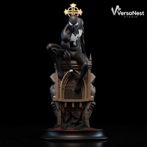 Puede incluir: Estatua negra de Spider-Man con detalles blancos, posada sobre una base de estilo gótico. La estatua tiene una cruz dorada y está sobre un fondo negro. El logotipo de VersaNest Studio es visible.
