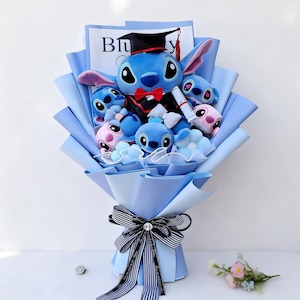 May include: A bouquet of blue plush Stitch characters, some wearing graduation attire. The bouquet is wrapped in light blue paper and tied with a striped ribbon and bow. The central Stitch figure wears a graduation cap and gown.