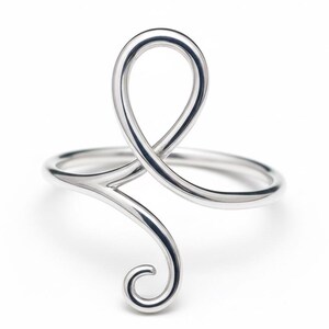 May include: A silver ring with a distinctive, flowing design. The ring has a looped top and a swirling, open design. The metal is polished, reflecting light. The ring's design is modern and artistic, suitable for everyday wear.