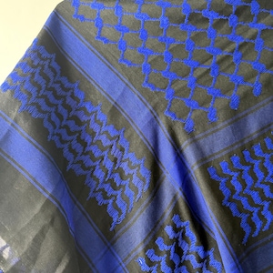 May include: A blue and black keffiyeh scarf with a geometric pattern. The scarf features a repeating design of blue squares and lines against a black background. The scarf is made of a soft material.