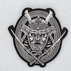 Könnte beinhalten: Schwarz-weißer Aufnäher mit einer detaillierten Illustration einer Samurai-Maske mit Helm und gekreuzten Schwertern. Das Design ist in einem kreisförmigen Rahmen mit komplizierten Mustern gehalten und erzeugt ein auffälliges Bild.