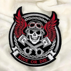 以下が含まれることがあります： 黒と赤の刺繍パッチ。ヘルメットとゴーグルを着用したスカル、赤い翼、交差したピストンが特徴です。「RIDE OR DIE」の文字が白で表示されています。パッチは黒い縁取りのある円形デザインです。
