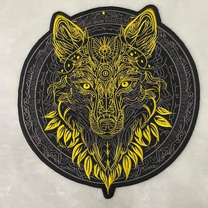 May include: Embroidered patch featuring a stylized wolf head in yellow thread on a black circular background. The wolf has detailed facial features and is surrounded by intricate patterns. The patch is suitable for jackets, bags, or other fabric items.