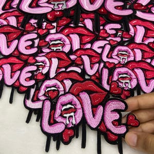 May include: Embroidered patches with the word "LOVE" in pink bubble letters, red lips, and dripping black accents. Each patch includes a heart detail. Ideal for customising clothing or accessories.