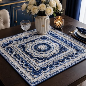 May include: A square crochet table topper featuring an intricate mandala pattern in deep navy blue and cream white yarn. The design includes concentric layers of scalloped edges, floral motifs, and geometric borders, creating a textured surface.