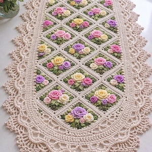 Op de afbeelding: Crèmekleurige, gehaakte tafelloper met een centraal patroon van ruitvormige blokken, elk versierd met een tros kleurrijke rozen in roze, geel en paars. De randen zijn afgewerkt met een decoratieve, geschulpte rand.