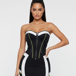 May include: Black and white strapless corset top and matching skirt. The corset features a zipper closure, white trim, and yellow accents. The skirt has white side panels.