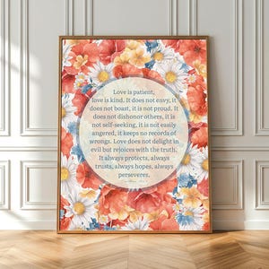 Puede incluir: Una impresión floral enmarcada con un diseño de acuarela de flores rojas, naranjas, amarillas y blancas. La obra de arte incluye una superposición de texto circular central con las palabras "Love is patient, love is kind..." en fuente azul claro.