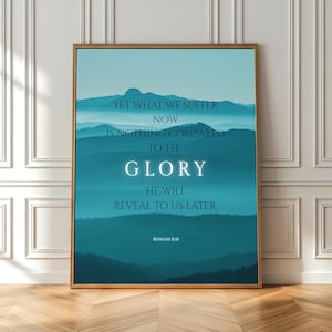 Könnte beinhalten: Ein gerahmter Kunstdruck mit goldenem Rahmen. Das Kunstwerk zeigt eine blau-türkise Berglandschaft mit weißem Text, der lautet: "YET WHAT WE SUFFER NOW IS NOTHING COMPARED TO THE GLORY HE WILL REVEAL TO US LATER." Römer 8:18.