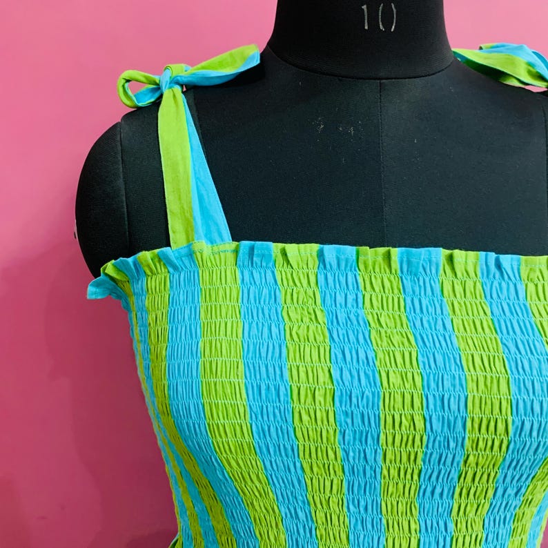 Puede incluir: Top a rayas azules y verdes con tirantes anudados. El top se muestra en un maniqu&iacute; negro. Las correas son verdes por fuera y azules por dentro. El top tiene un dise&ntilde;o fruncido.