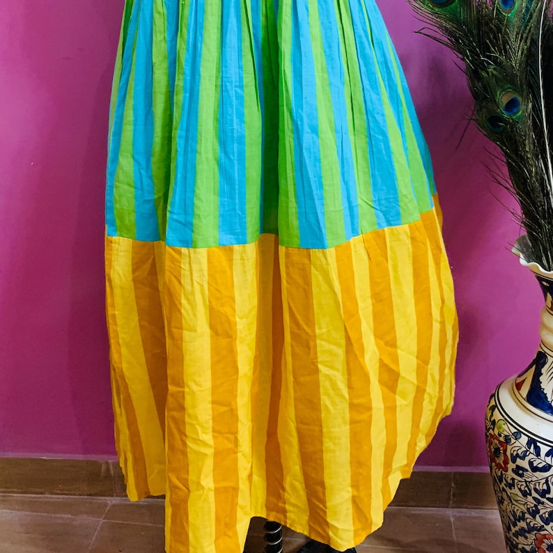 Puede incluir: Falda larga con rayas verticales en amarillo, azul y verde. La falda est&aacute; hecha de una tela ligera y tiene una silueta completa y fluida. Es una prenda vibrante y llamativa. La falda es una prenda colorida.