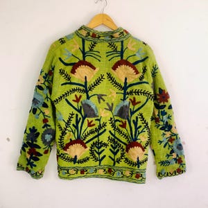 May include: A lime green jacket with intricate floral embroidery in shades of brown, blue, and yellow. The jacket features a mandarin collar and long sleeves, with the floral design covering the front and sleeves.