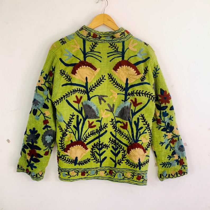 May include: A lime green jacket with intricate floral embroidery in shades of brown, blue, and yellow. The jacket features a mandarin collar and long sleeves, with the floral design covering the front and sleeves.