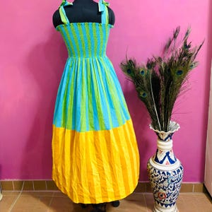 Puede incluir: Un vestido de verano a rayas de colores en un maniqu&iacute;. El vestido presenta un corpi&ntilde;o a rayas azules y verdes, una falda a rayas azules y verdes y un dobladillo a rayas amarillas. El vestido tiene tirantes verdes.