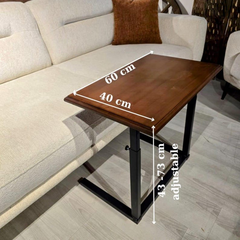 May include: A rectangular side table with a dark brown wooden top and a black metal frame. The table top measures 60 cm by 40 cm. The height is adjustable between 43 cm and 73 cm, as indicated by the text and arrows on the image.