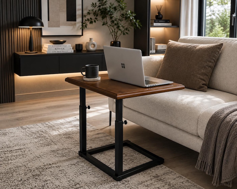 May include: A rectangular wooden side table with a dark brown finish and a black metal frame. The table features an adjustable height mechanism with visible knobs on the vertical supports. A silver laptop and a black mug are placed on the surface.