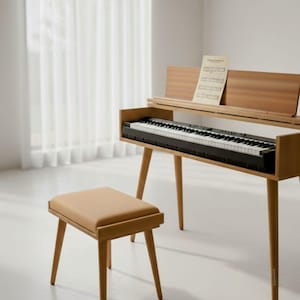 May include: A wooden piano with a black and white keyboard, a music stand, and a matching stool. The piano has a light brown finish and is set against a white background. Sheet music rests on the stand.