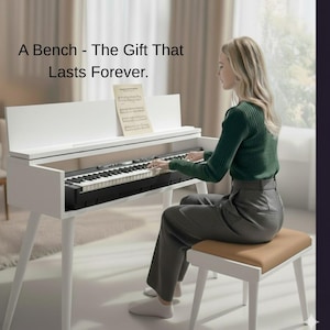 May include: A white piano with black and white keys, and a matching bench. The piano has a music stand with sheet music. The text on the image reads: "A Bench - The Gift That Lasts Forever."