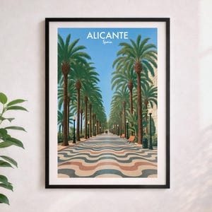 May include: Framed art print of Alicante, Spain, showing a palm-lined promenade with a patterned walkway, benches, and streetlights under a blue sky. The word "ALICANTE" is displayed at the top of the print.