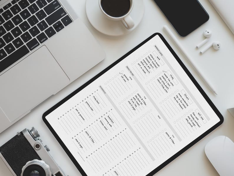 May include: An overhead shot of a workspace featuring a laptop, tablet, camera, phone, and coffee cup. The tablet displays a daily planner with sections for tasks and schedules. A stylus and wireless earbuds are also present.