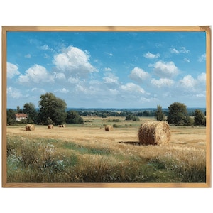 Op de afbeelding: Een ingelijst landschapsschilderij toont een zonnig veld met hooibalen onder een blauwe lucht met witte wolken. Het kunstwerk toont een boerderij en bomen op de achtergrond, in een natuurlijke houten lijst.