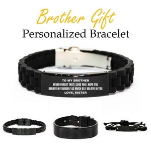 May include: Black personalized bracelet with a stainless steel clasp. The bracelet has a black rubber band and a black metal plate with the text "TO MY BROTHER...LOVE, SISTER". Additional bracelets are shown below.