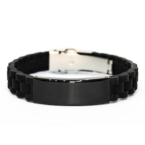May include: A black silicone bracelet with a stainless steel clasp. The bracelet features a rectangular black plate in the center. The band has a textured, segmented design. The bracelet is shown against a white background.