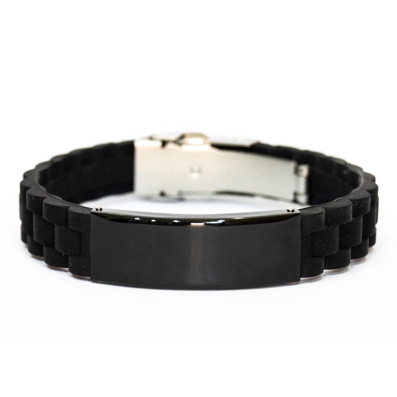 May include: A black silicone bracelet with a stainless steel clasp. The bracelet features a rectangular black plate in the center. The band has a textured, segmented design. The bracelet is shown against a white background.