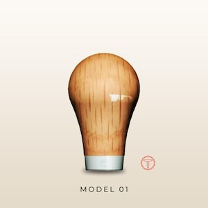 May include: A light brown wooden gear shift knob with a smooth, rounded top and a vertical grain pattern. The base features a metallic silver band with a small circular logo. Below the object, the text MODEL 01 is printed in black capital letters.