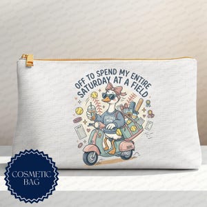 May include: A white cosmetic bag featuring a graphic of a duck wearing sunglasses and a bow, riding a scooter. The duck wears a sweatshirt labeled Softball Mom and carries a bag with softballs. Text reads: Off to spend my entire Saturday at a field.