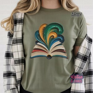 May include: Army green t-shirt featuring a colorful graphic of an open book with swirling paint in shades of blue, green, and gold. The shirt has the word "Army" printed on it. The brand name "Cotton & Chaos" is printed on the bottom right.