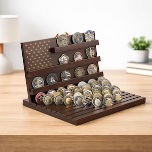 May include: A wooden coin display stand with multiple shelves, holding a collection of various coins. The stand features a design of the American flag with gold stars. The coins are of different colors and designs.