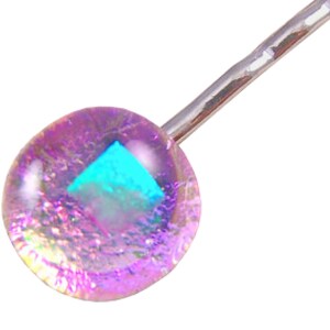 May include: A shimmering bobby pin featuring a round, iridescent charm. The charm has a clear, bubble-like appearance with a vibrant, turquoise-colored square embedded within. The metal pin is silver-toned.