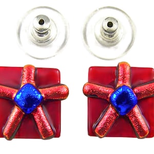 May include: A pair of red square stud earrings with a starburst design. The starburst is red with a textured, glittery appearance, and a blue center. The earrings have clear, plastic backings and silver posts.