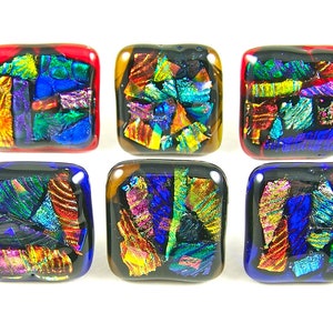 May include: Six square glass art pieces with rounded corners. Each piece has a black base with colorful, iridescent glass shards in shades of blue, green, red, and gold. The edges are framed in red, blue, and brown.