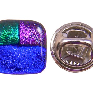 May include: A square dichroic glass pin with a silver pin back. The glass is divided into three sections: blue, green, and purple. The pin is a decorative accessory.