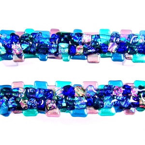 May include: Two rectangular glass hair barrettes. Each barrette is composed of a series of rectangular glass pieces in shades of blue, teal, and pink. The center of each barrette is filled with a mosaic of iridescent glass.