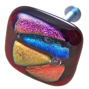 May include: Square cabinet knob with a dark red base and multi-coloured glass inlay. The inlay features a layered design of pink, blue, gold, and orange.