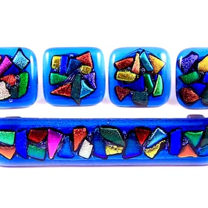 Peut inclure: Ensemble de cinq boutons de cabinet en verre bleu avec des motifs géométriques colorés. Les boutons sont de forme carrée et rectangulaire.