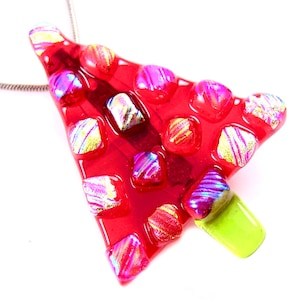 May include: A red glass pendant with a silver chain. The pendant is shaped like an arrow with colorful, iridescent squares embedded in the red glass. The tip of the arrow is a bright green color.