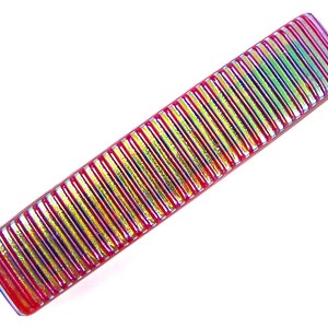 May include: A rectangular, iridescent glass comb with a ridged design. The comb features a vibrant color palette of red, yellow, and green hues. The comb is set against a white background.