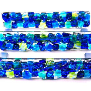 May include: Three rectangular glass cabinet pulls with a mosaic design. The pulls are primarily blue, with accents of turquoise and yellow-green. The glass is clear, and the pulls have a light blue base.