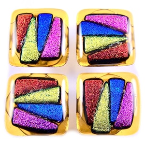 May include: Four square glass art pieces with a gold border. Each piece features a colourful, abstract design with red, blue, green, and purple glittery segments. The pieces are arranged in a 2x2 grid against a white background.